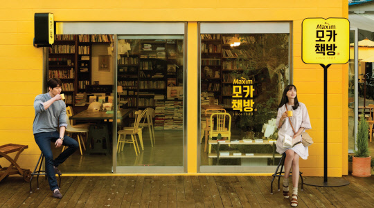 동서식품이 지난 4월부터 이달 6일까지 서울 성수동에서 한시적으로 운영한 팝업스토어형 북카페 '모카책방' 앞에서 광고 모델인 배우 이나영(오른쪽)과 김우빈이 커피 잔을 들고 포즈를 취하고 있다. <동서식품 제공>